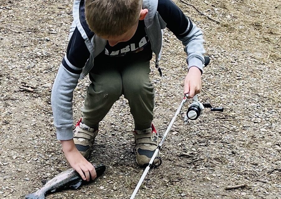 Billede af en dreng der har fanget en regnbue ørred